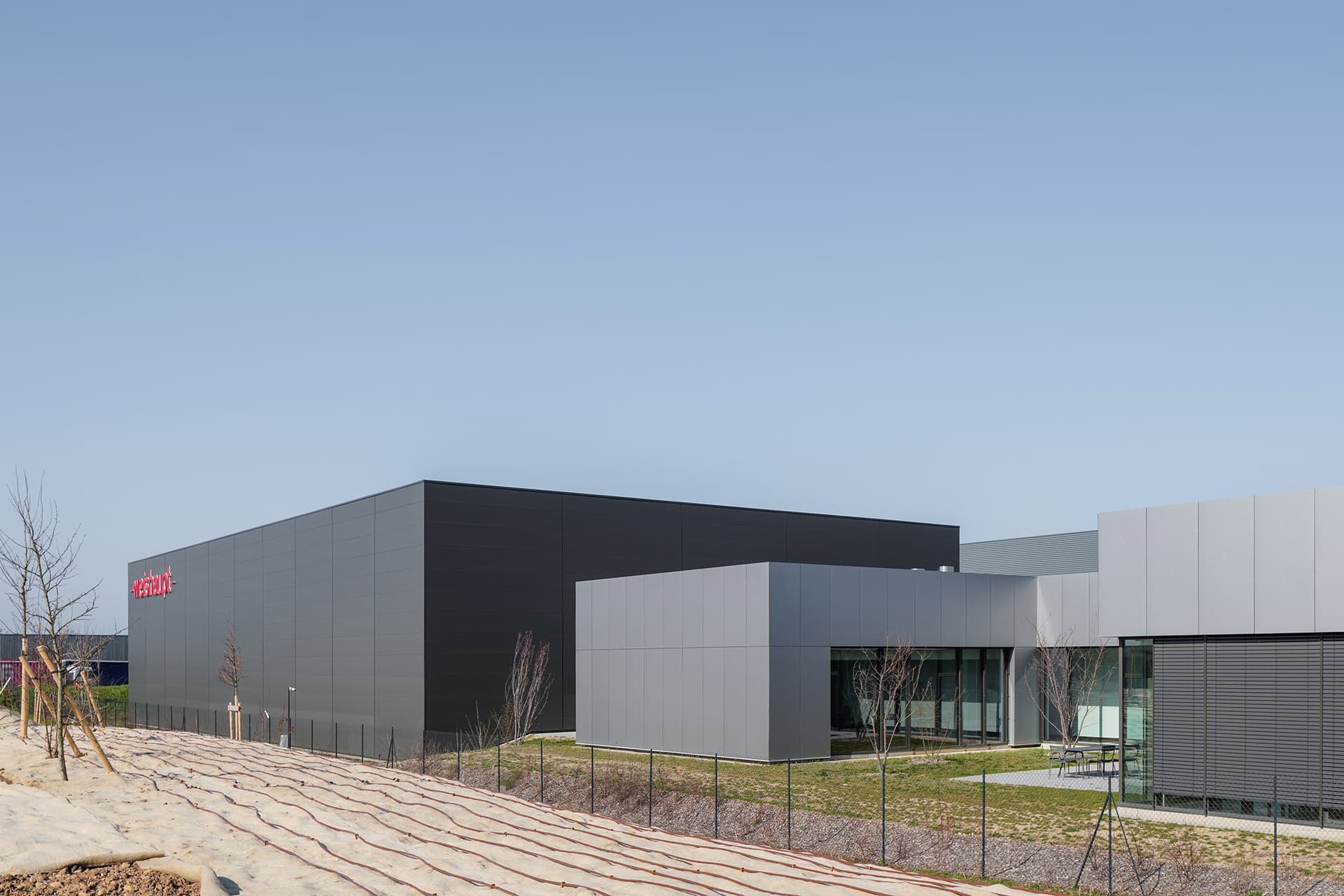 À l'extérieur, les bâtiments tertiaires et industriels sont gris clair et foncé avec Weishaupt en rouhe.